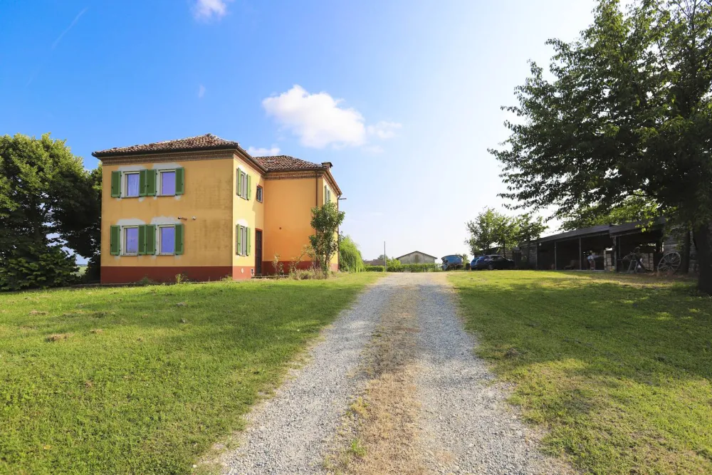 Rustic dream home in Italy – 3,000 m² surrounded by greenery with panoramic views, farmhouse with gravel driveway and outbuildings.