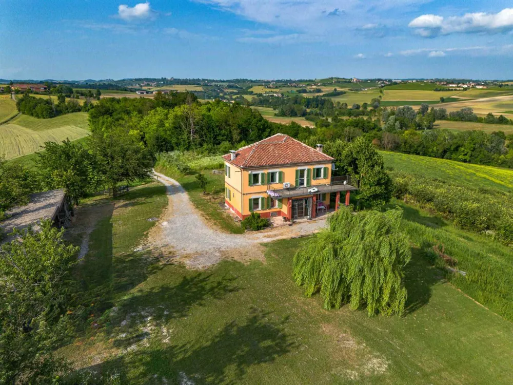 Rustic dream home in Italy – 3,000 m² surrounded by greenery with panoramic views, aerial view of the house and rolling hills.