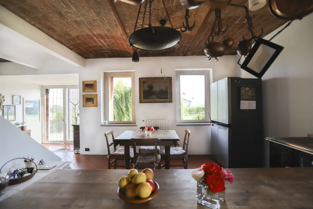 Rustic dream home in Italy – 3,000 m² surrounded by greenery with panoramic views, dining room with wooden table, fruit bowl and rustic ceiling.