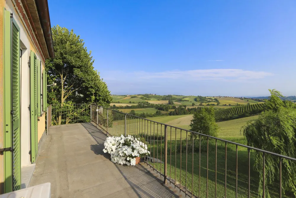 Rustic dream home in Italy – 3,000 m² surrounded by greenery with panoramic views, balcony overlooking rolling hills.