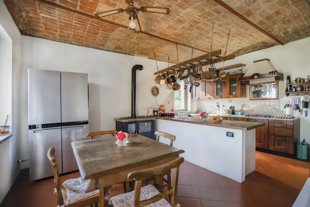 Rustic dream home in Italy – 3,000 m² surrounded by greenery with panoramic views, kitchen with wooden furniture and large fridge.