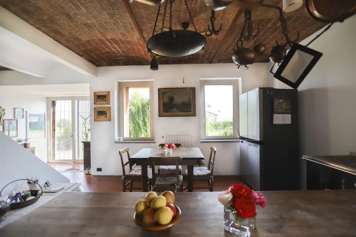 Rustic dream home in Italy – 3,000 m² surrounded by greenery with panoramic views, dining room with wooden table, fruit bowl and rustic ceiling.