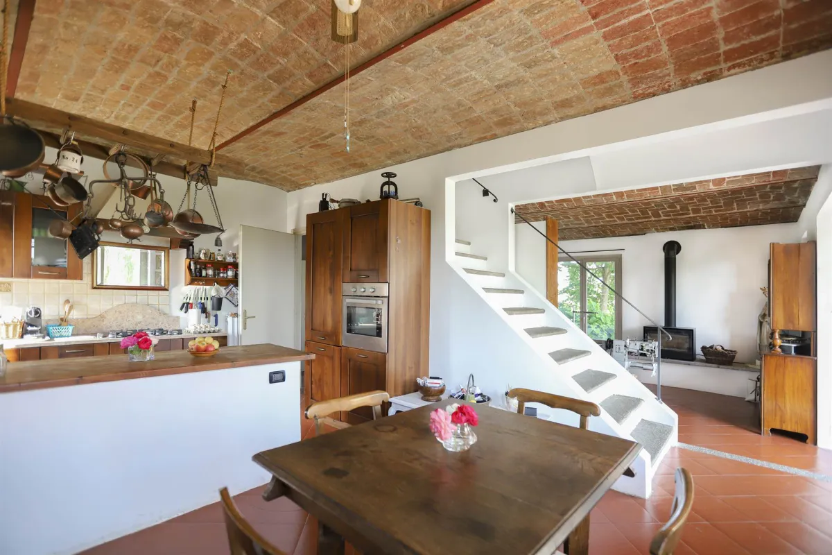 Rustic dream home in Italy – 3,000 m² surrounded by greenery with panoramic views, kitchen with dining table and staircase.