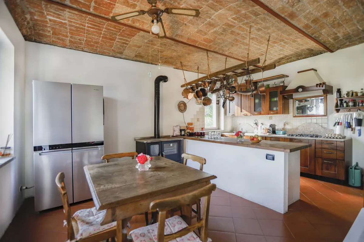 Rustic dream home in Italy – 3,000 m² surrounded by greenery with panoramic views, kitchen with wooden furniture and large fridge.