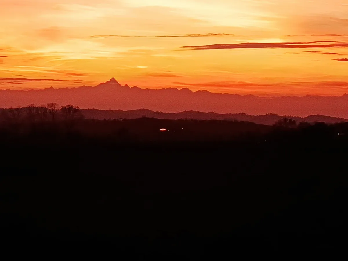Rustic dream home in Italy – 3,000 m² surrounded by greenery with panoramic views, sunset over the mountains with glowing sky.