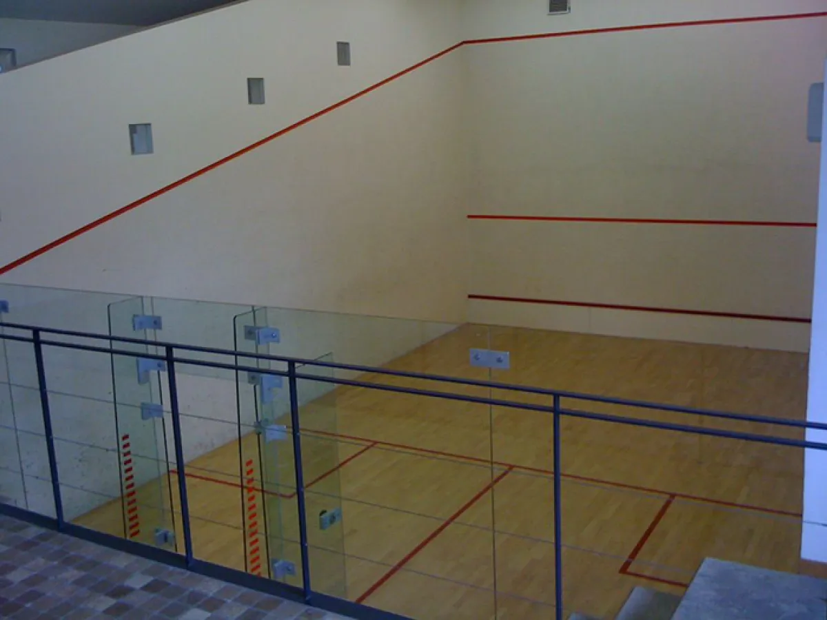 Campo da squash nel residence con parete in vetro e linee di demarcazione del campo